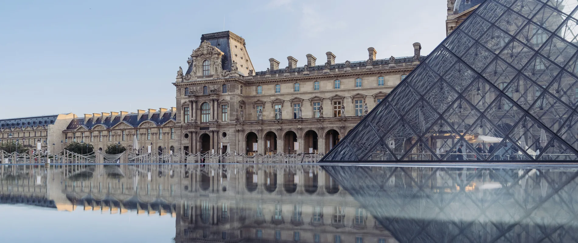 Le mus&eacute;e du Louvre et sa pyramide en verre se refl&egrave;tent dans l'eau.