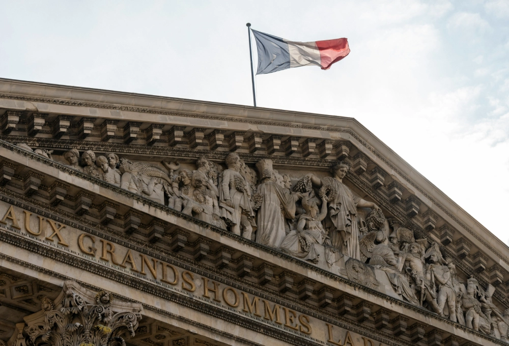 Fronton sculpt&eacute; avec drapeau fran&ccedil;ais flottant au-dessus.
