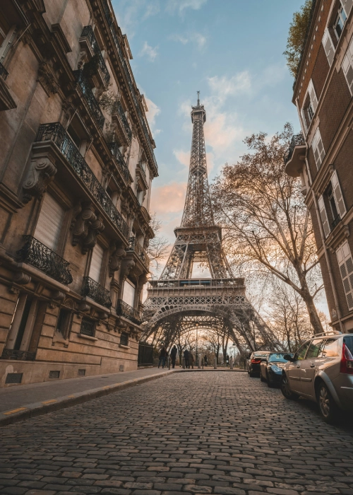 Rue pav&eacute;e avec la Tour Eiffel en arri&egrave;re-plan au cr&eacute;puscule.