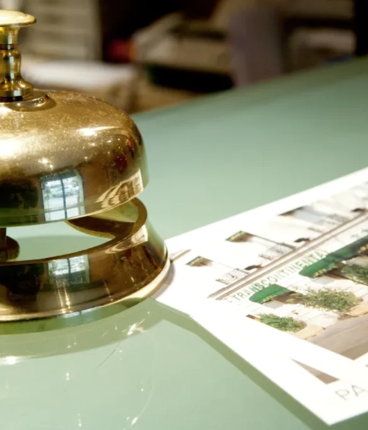 Cloche de r&eacute;ception en m&eacute;tal sur un comptoir &agrave; c&ocirc;t&eacute; d'un d&eacute;pliant d'h&ocirc;tel.