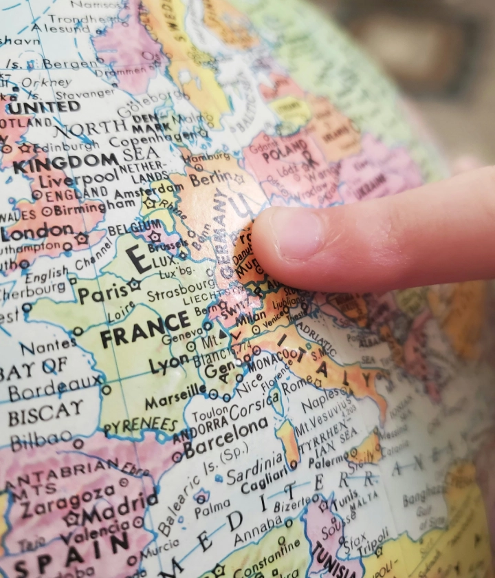 Un doigt pointe vers l'Europe sur un globe terrestre.