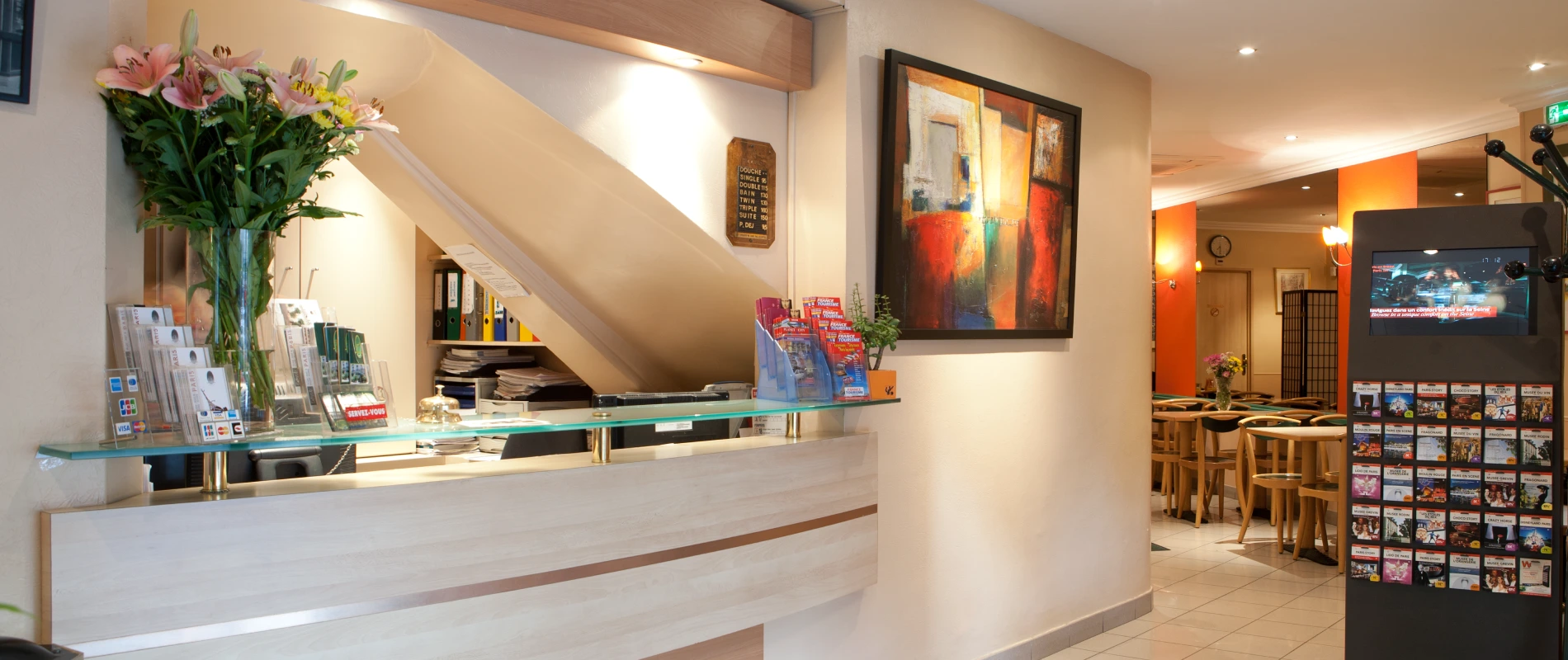 R&eacute;ception d&rsquo;h&ocirc;tel moderne avec fleurs et affiches color&eacute;es.