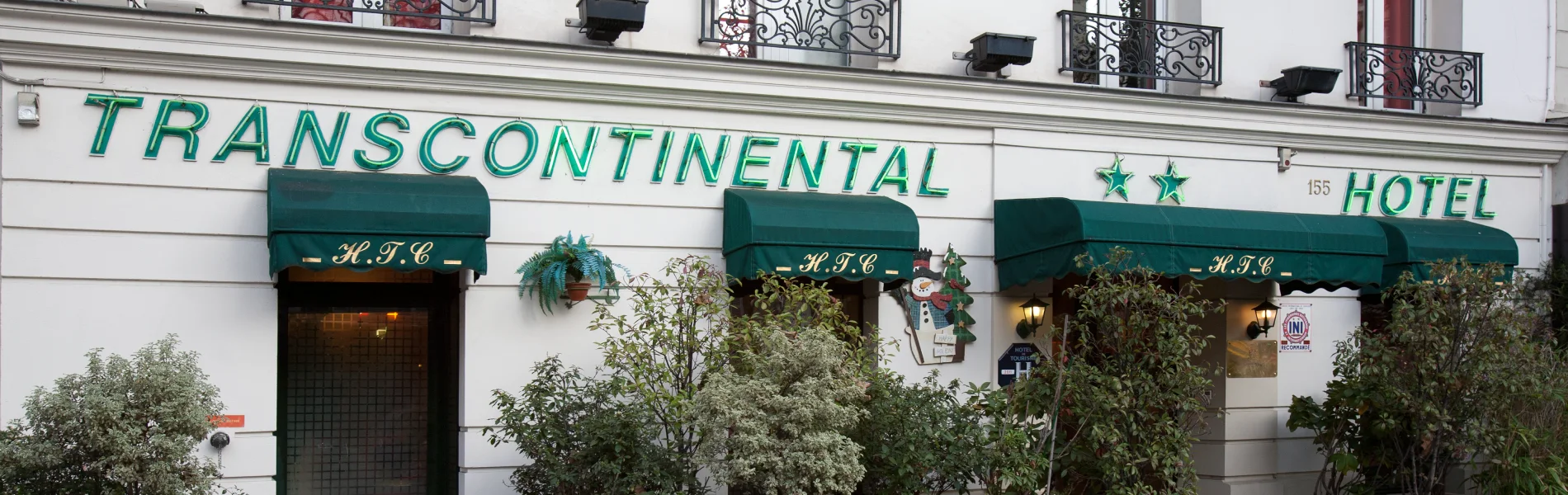 Fa&ccedil;ade de l'h&ocirc;tel Transcontinental avec deux &eacute;toiles et auvents verts.