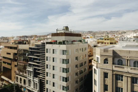 Edificios en una ciudad con cielo parcialmente nublado y colinas al fondo.