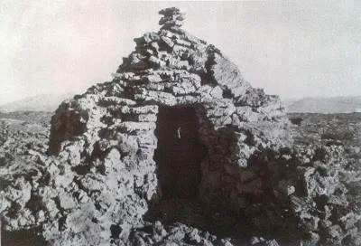 Estructura c&oacute;nica de piedras apiladas en un paisaje &aacute;rido, con una apertura en el centro.