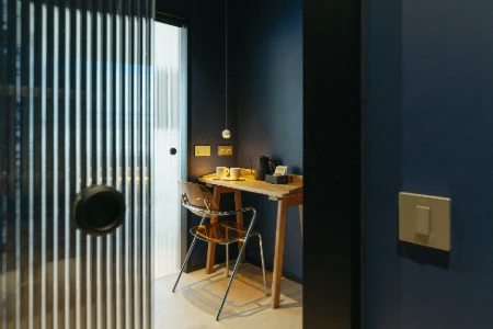 Escritorio con silla transparente y pared azul en habitaci&oacute;n moderna.