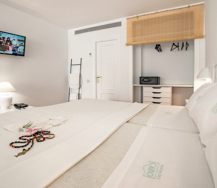 Habitaci&oacute;n luminosa con cama doble, TV, armario y decoraci&oacute;n sencilla.