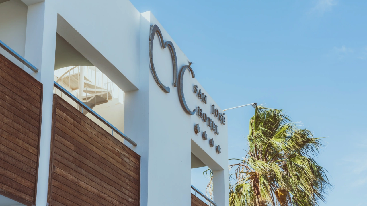 Fachada de un hotel moderno con palmeras y cielo despejado.