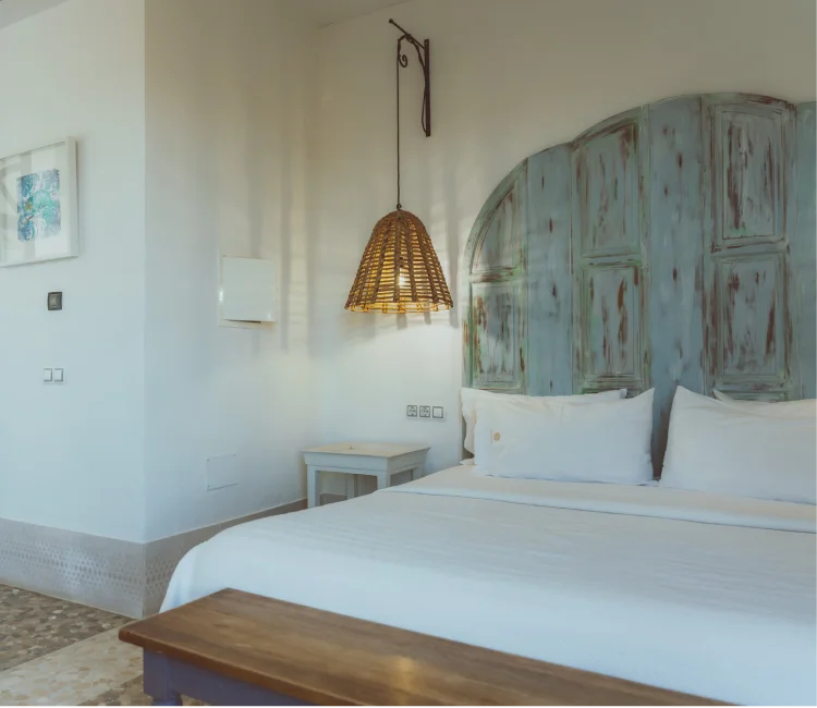 Habitaci&oacute;n luminosa con cama doble y l&aacute;mpara de mimbre colgante.