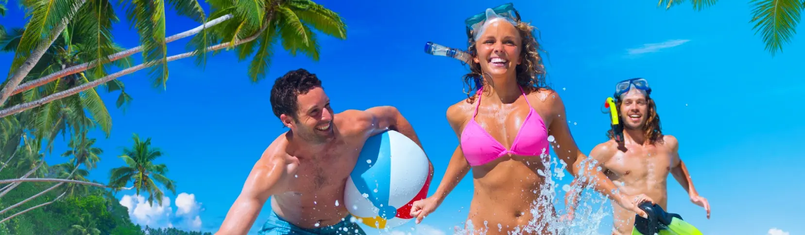 Personas con flotadores en el mar, bajo palmeras, sonriendo en el agua