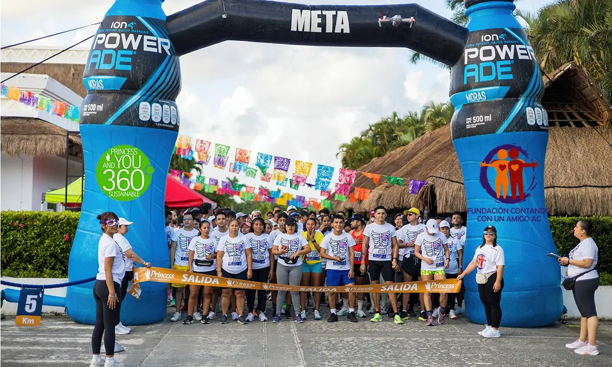 Participantes de carrera junto a arcos inflables azules &ldquo;Power Ade&rdquo; en evento solidario