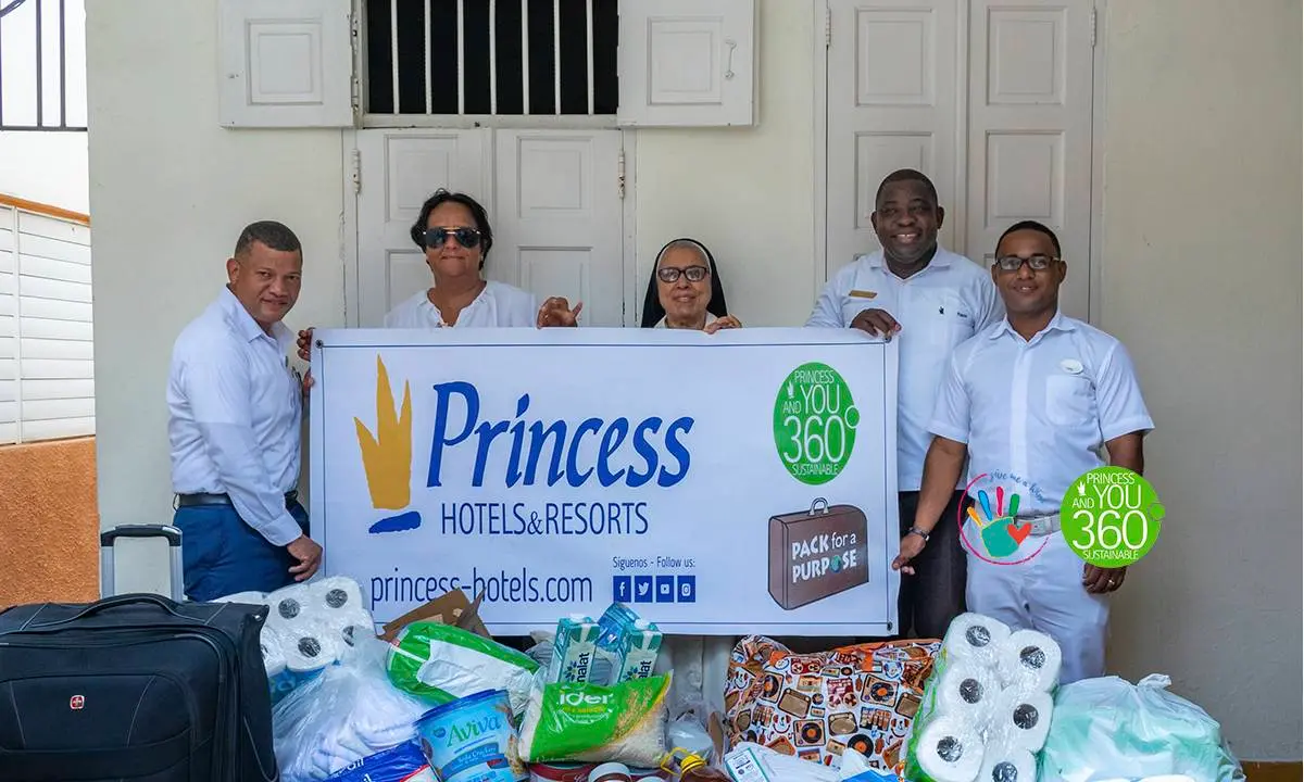 Equipo de hotel con cartel &ldquo;Princess Hotels & Resorts&rdquo; y donaciones frente a puertas