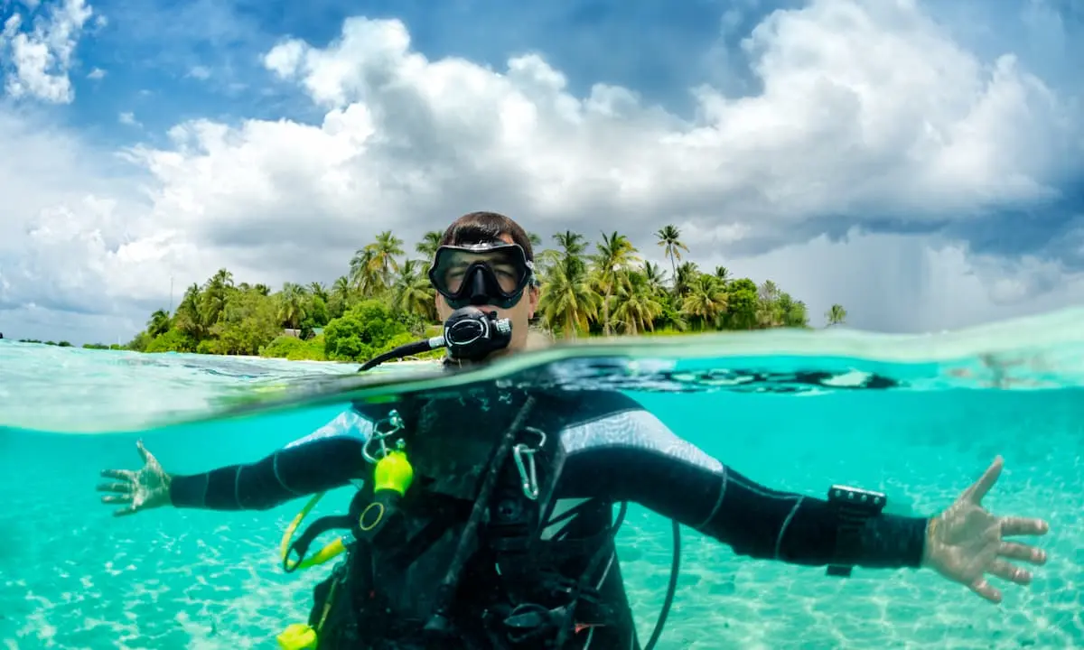 Buceador con m&aacute;scara y traje en el Caribe, rodeado de palmeras y mar turquesa
