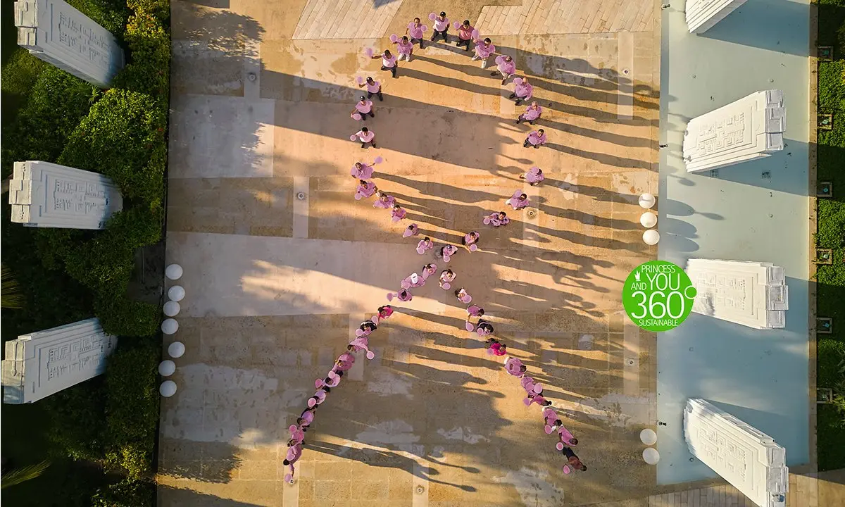 Vista a&eacute;rea de ni&ntilde;os formando un coraz&oacute;n en el patio, con luz solar y sombras.