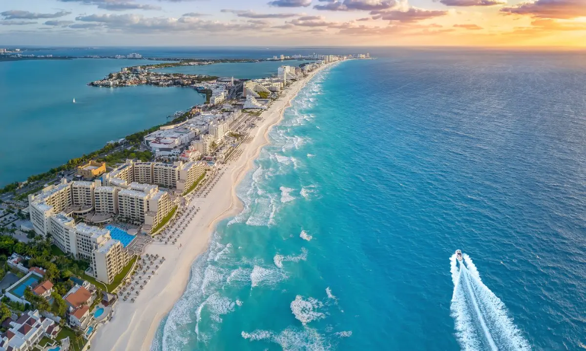 Costa urbana con hoteles y playa al atardecer, vista a&eacute;rea desde un barco