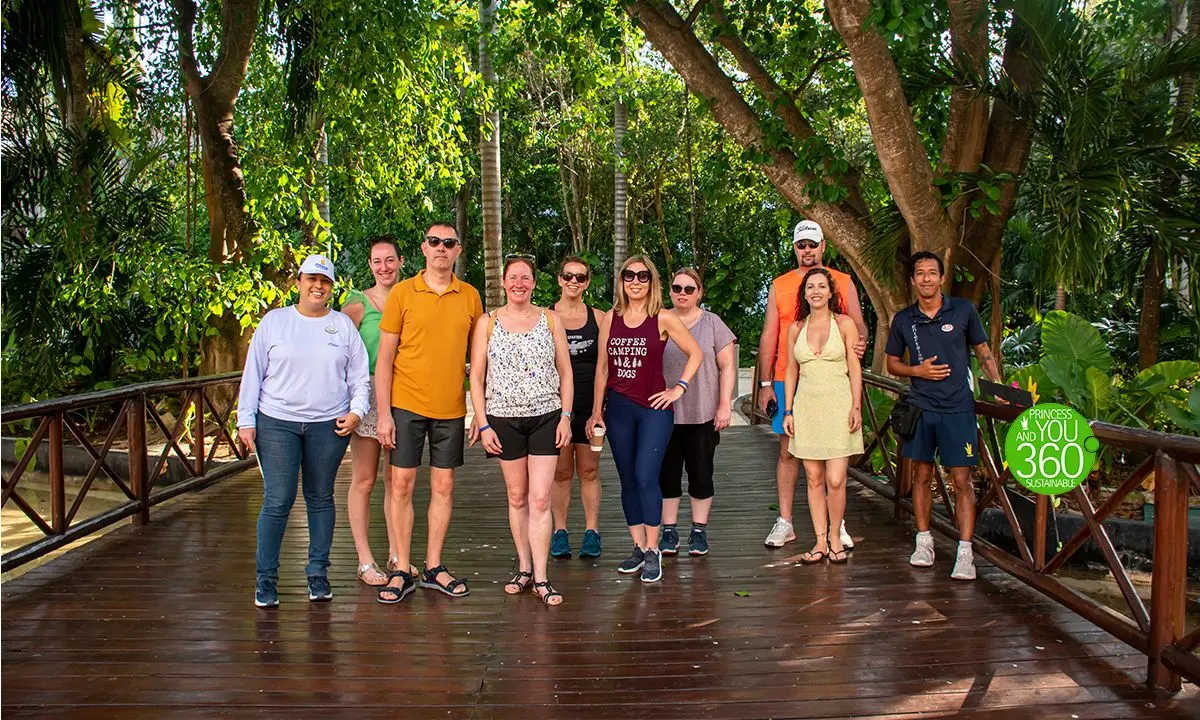 Grupo de personas posando en un puente de madera entre selva y &aacute;rboles tropicales.