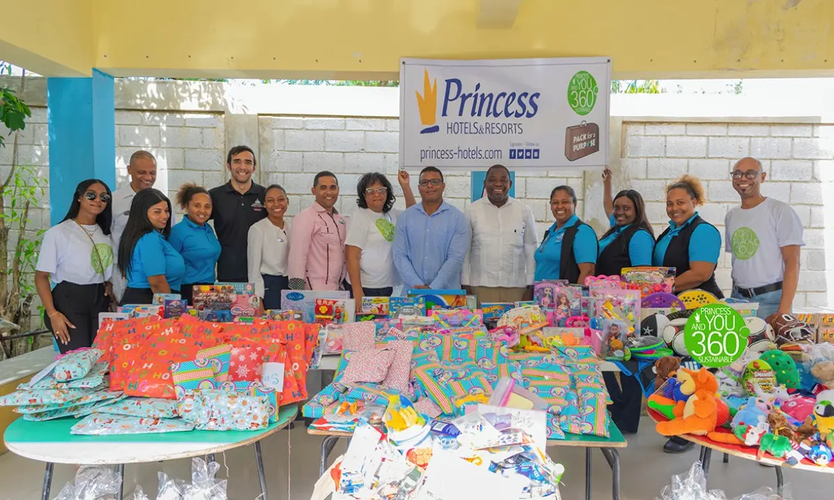 Grupo de personas con regalos y juguetes frente a banner de Princess Hotels.