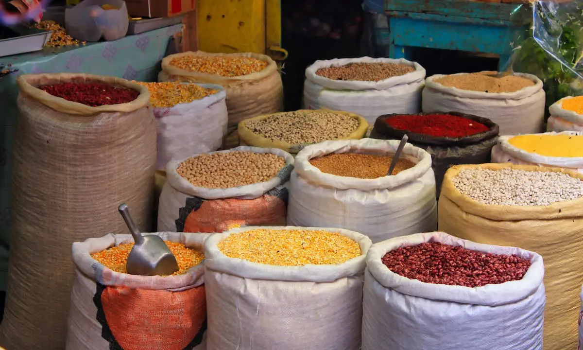 Sacos con granos y especias de colores en un mercado, primer plano.