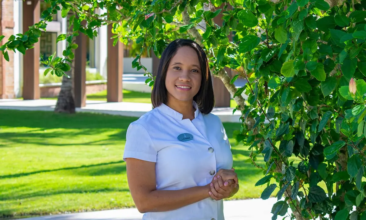 Retrato de una cocinera sonriente junto a un &aacute;rbol verde en jard&iacute;n soleado
