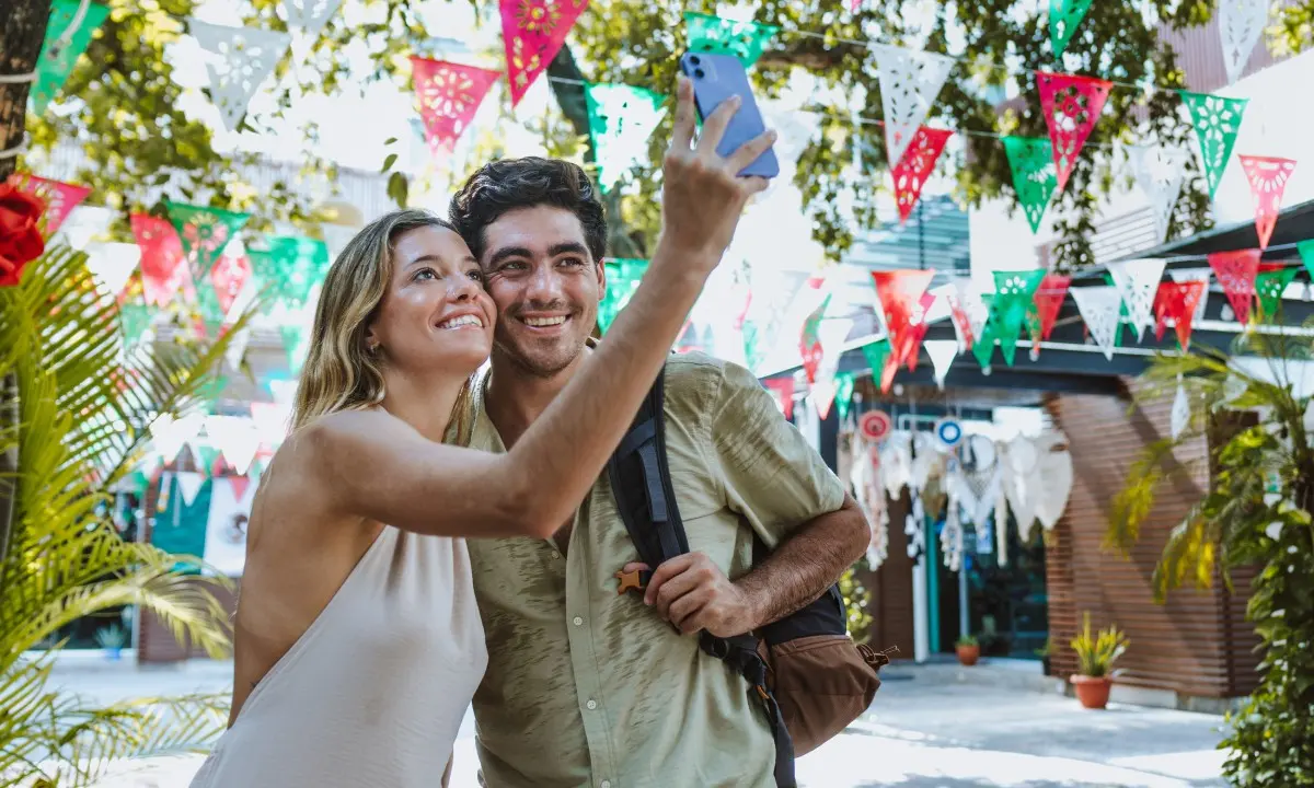 Pareja sonriente celebra con manos en alto bajo banderines coloridos.