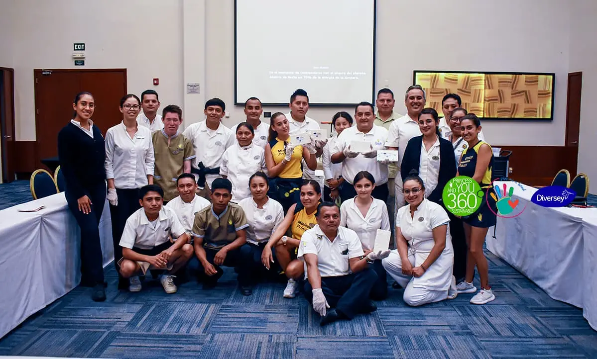 Grupo de personas uniformadas en sal&oacute;n, posando para foto grupal