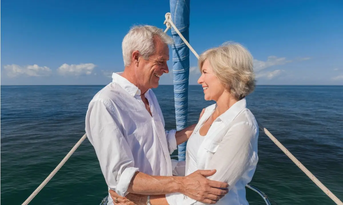 Pareja mayor sonriente a bordo de un barco en el mar, en un d&iacute;a soleado
