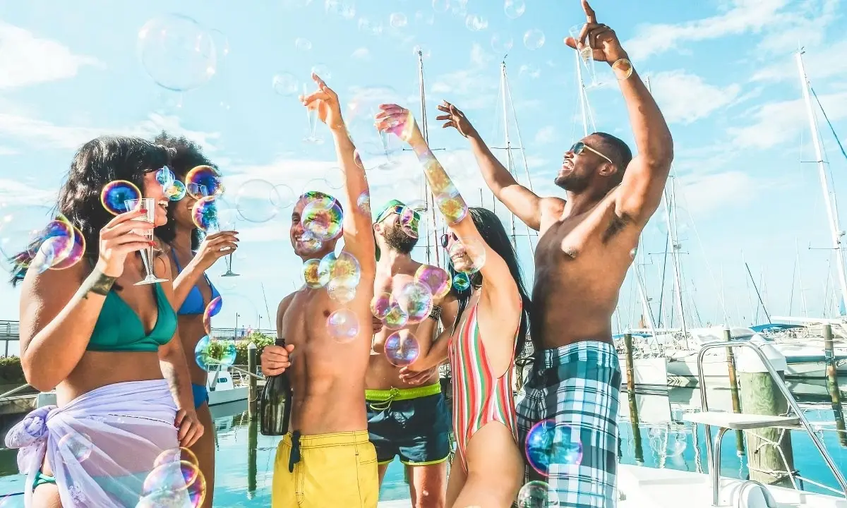 Grupo de j&oacute;venes celebrando con burbujas en un yate al aire libre
