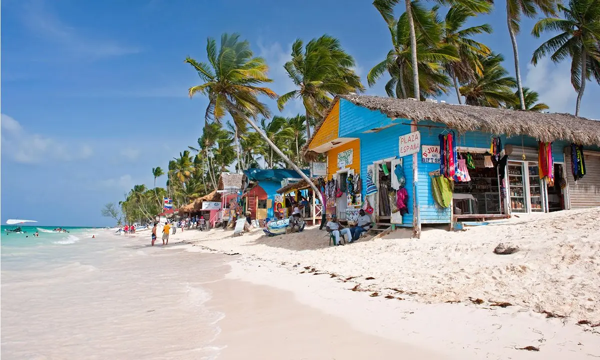 Playa tropical con palmeras y puestos coloridos junto a la orilla del mar