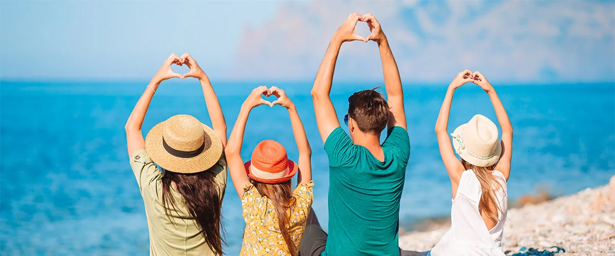 Familias forman corazones con las manos mirando al mar desde la playa
