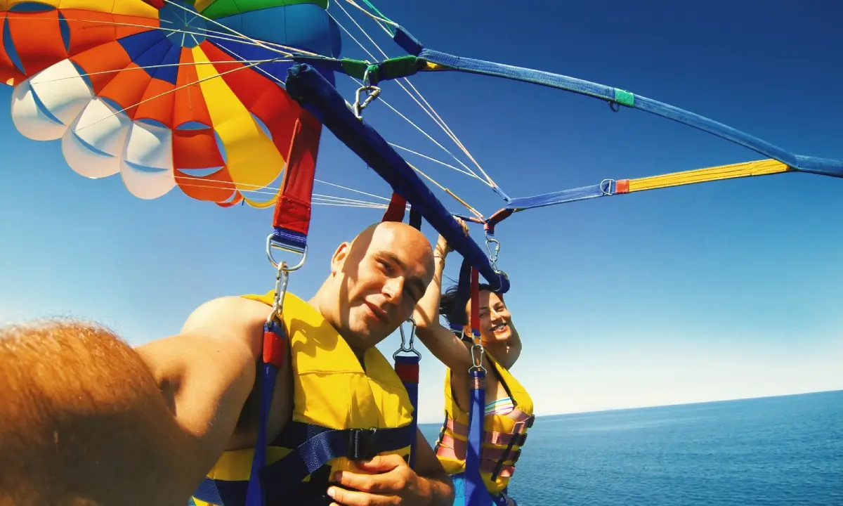 Pareja parasailing sobre las aguas de 7 Mile Beach