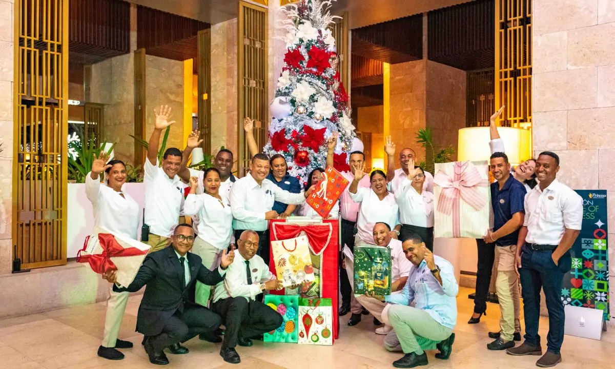 Grupo de personas con regalos y &aacute;rbol de Navidad decorado en un evento.