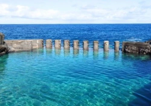 Mar azul con rompeolas y agua transparente frente al horizonte