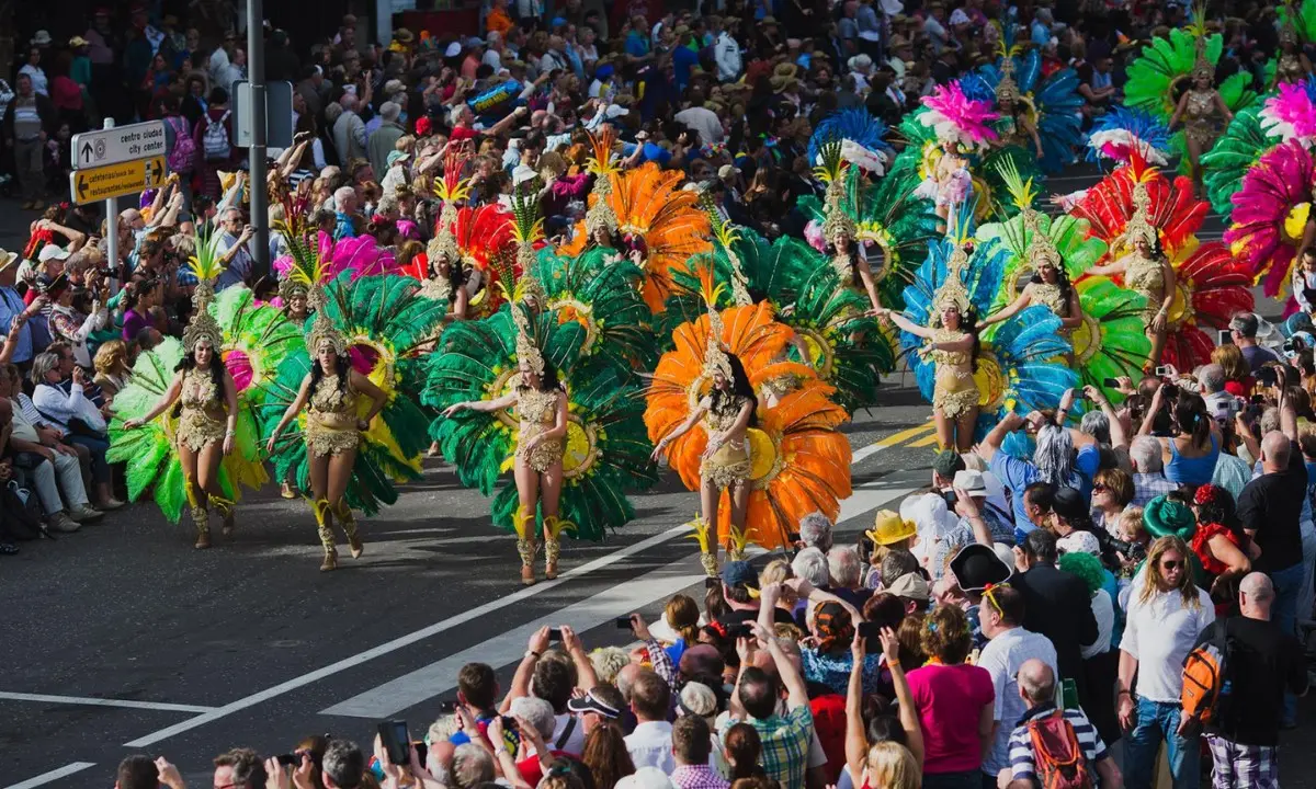 Desfile con bailarinas de samba con plumas de colores y multitud aplaudiendo