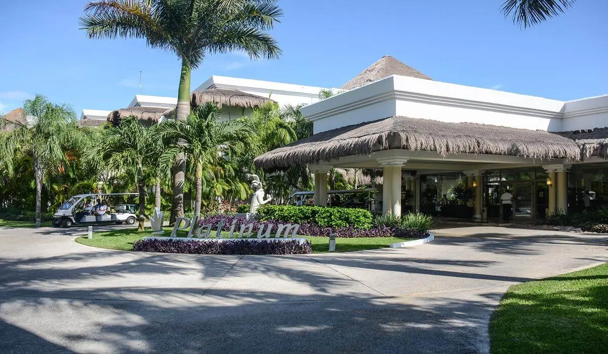 Hotel con palmeras, jard&iacute;n y techo de paja bajo cielo despejado