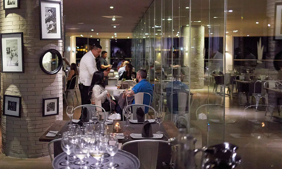 Camarero sirve en un comedor elegante con mesas y copas, de noche
