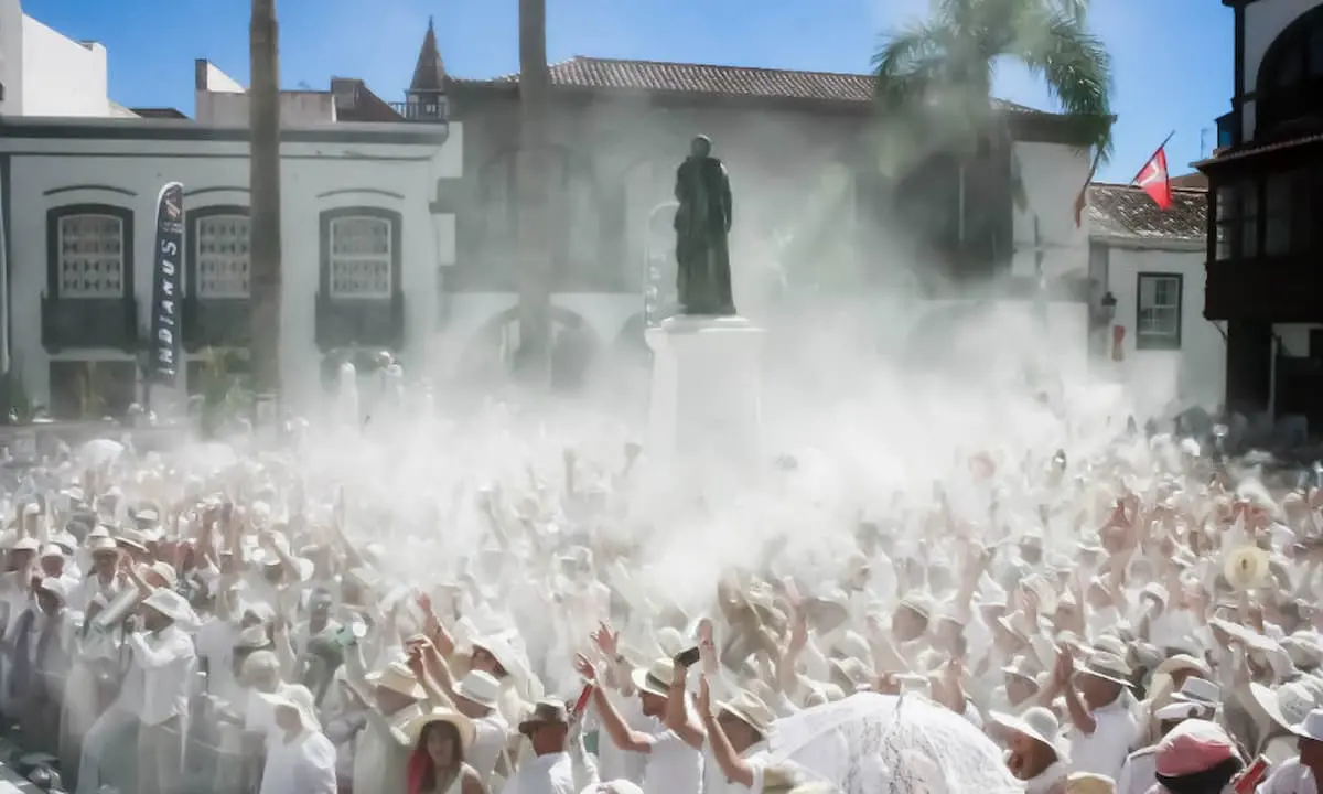 Multitud en desfile con estatuas y humo de confeti en plaza.