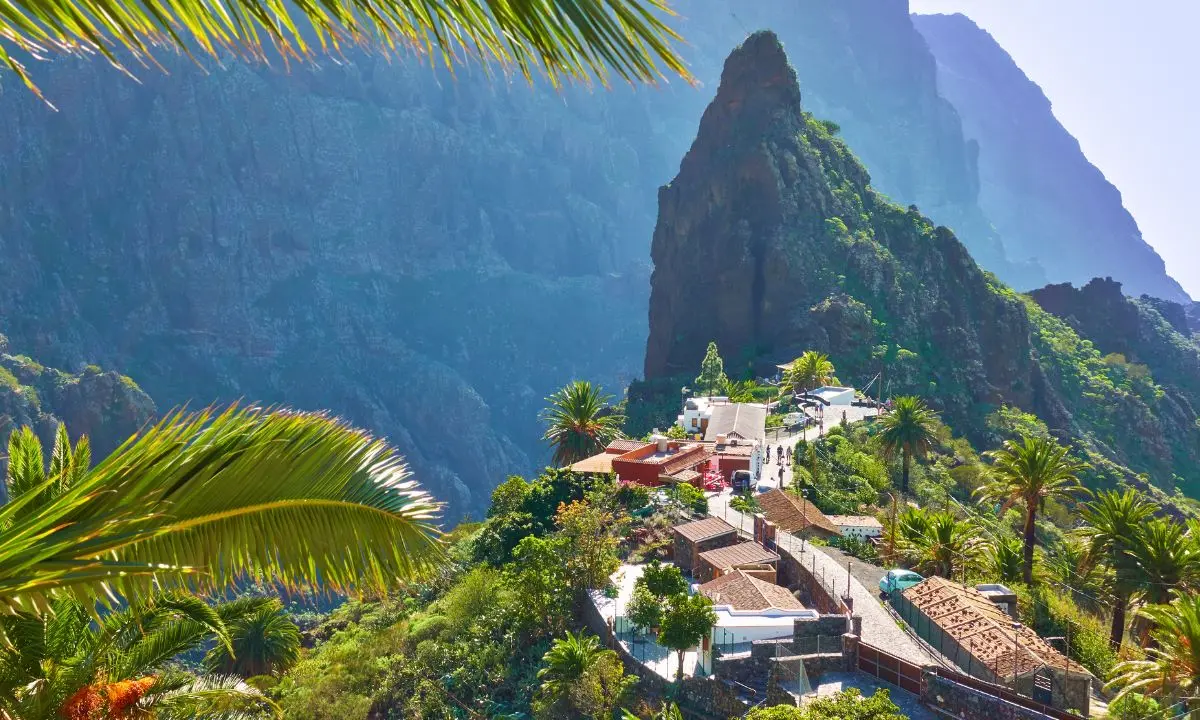 Pueblo tropical con palmeras y monta&ntilde;as verdes, vista panor&aacute;mica al atardecer