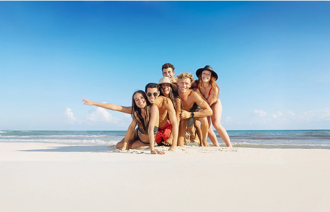 Grupo de amigos posando y sonriendo en la playa bajo el sol