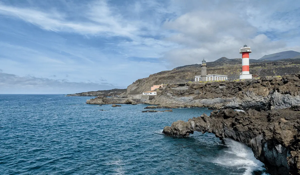 Faro blanco y rojo sobre acantilados volc&aacute;nicos frente al oc&eacute;ano Atl&aacute;ntico