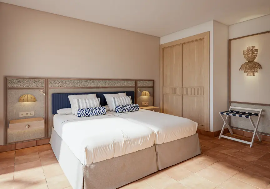 Dormitorio con cama doble, mesitas y l&aacute;mparas doradas, estilo moderno.