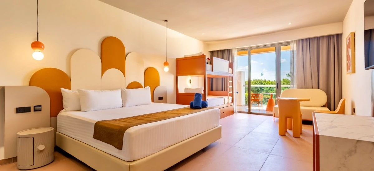 Dormitorio moderno con cama, sillas infantiles y acceso a balc&oacute;n con vistas