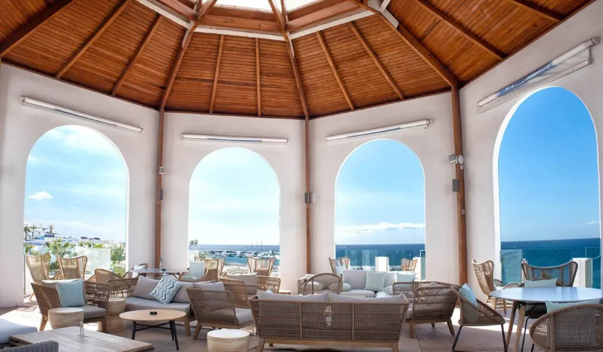 Terraza con muebles de mimbre y vista al mar, techos de madera y arcos