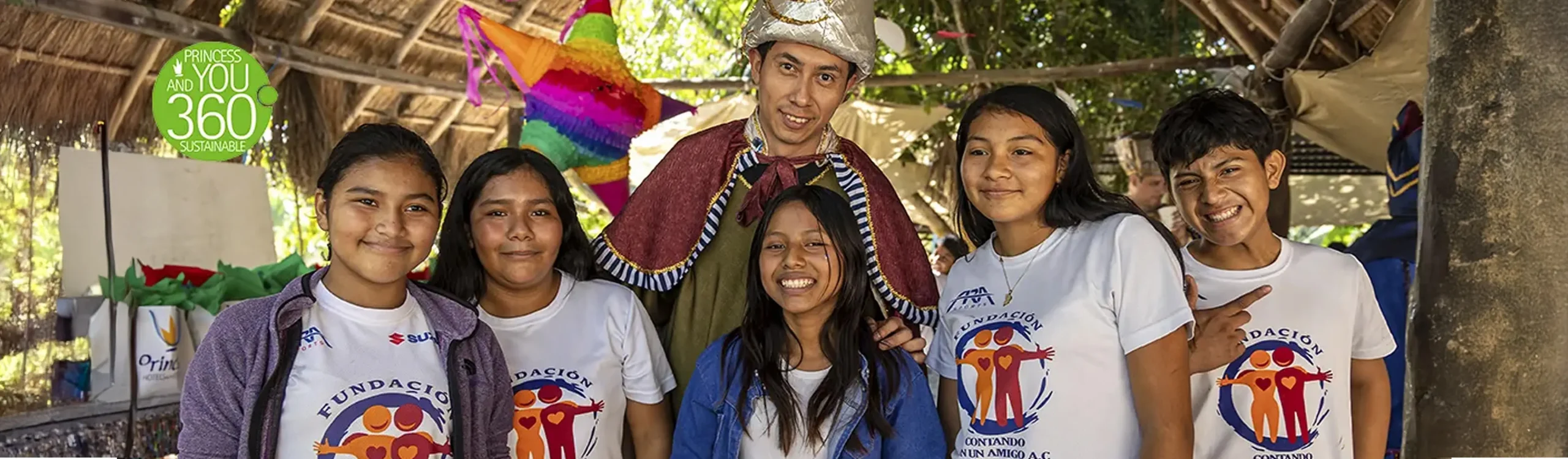 Familia de ni&ntilde;os y un adulto con sombrero, bajo un toldo, en evento al aire libre