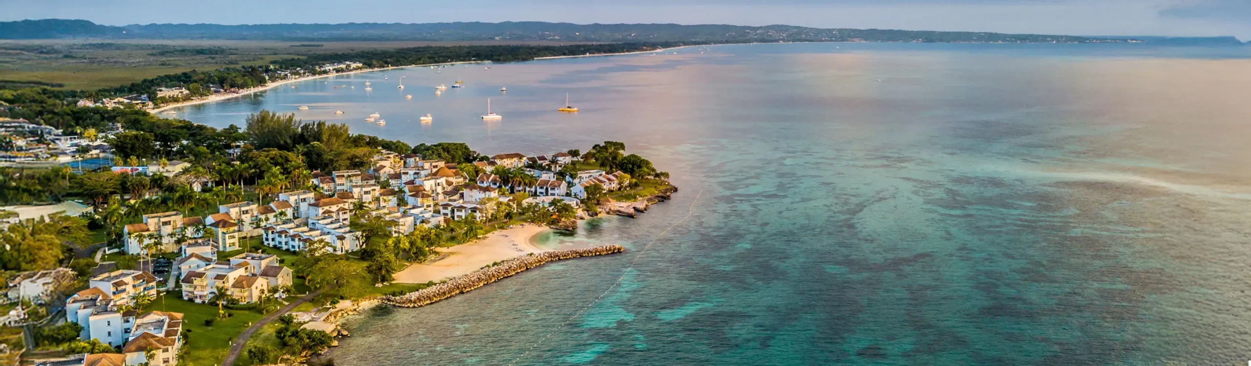 Vista a&eacute;rea de una bah&iacute;a costera con casas, muelle y botes en el agua