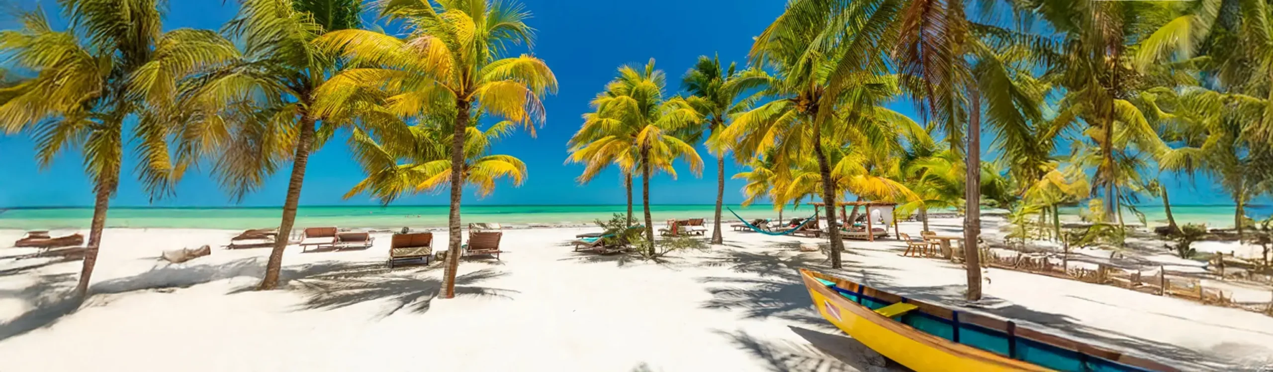 Playa tropical con palmeras, hamacas y barcas de colores junto al mar turquesa