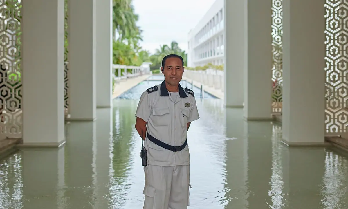 Guardia de seguridad con uniforme blanco en un pasillo con reflejos
