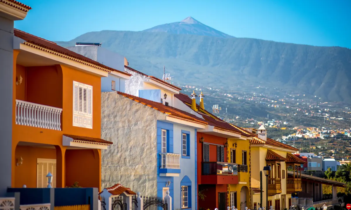 Casas coloniales de colores en una calle con el volc&aacute;n al fondo, paisaje costero