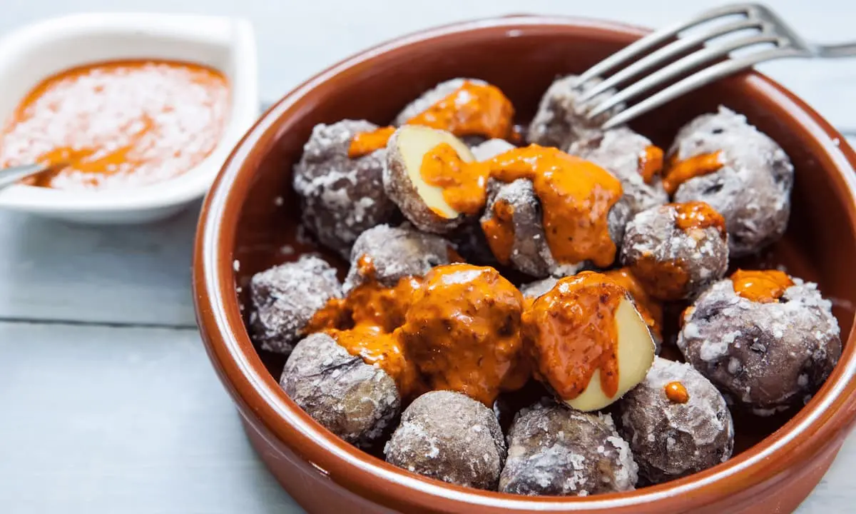 Taz&oacute;n con alb&oacute;ndigas de cerdo cubiertas con salsa naranja, con trozos de queso.