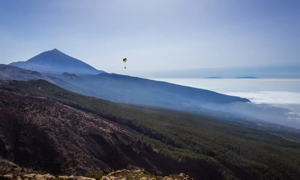 Monta&ntilde;a con valle y paracaidista sobre el oc&eacute;ano desde un mirador