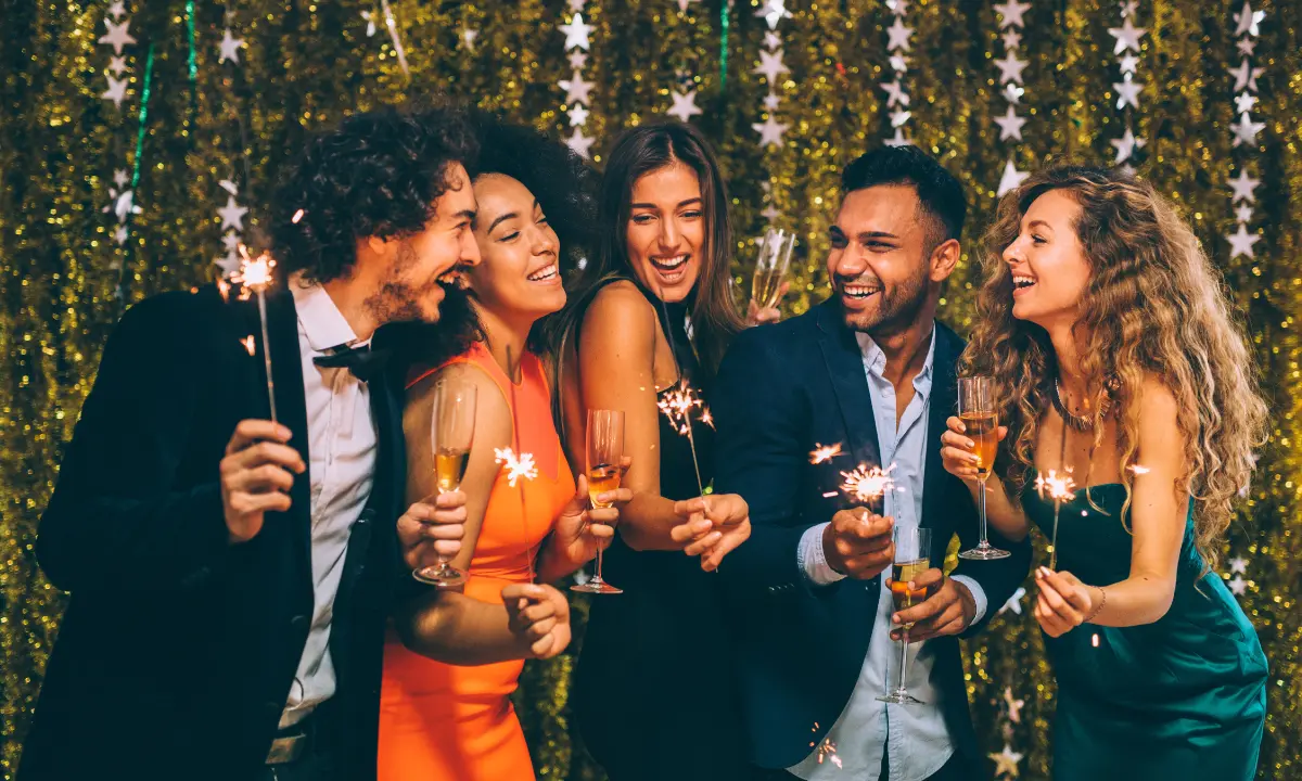 Personas brindando con champ&aacute;n y fuegos artificiales en una fiesta navide&ntilde;a, 2021